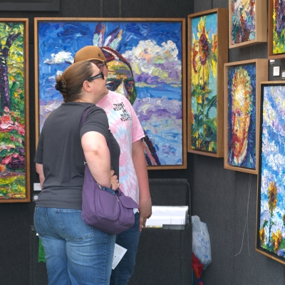 Two people looking at paintings at the Mulvane Art Fair